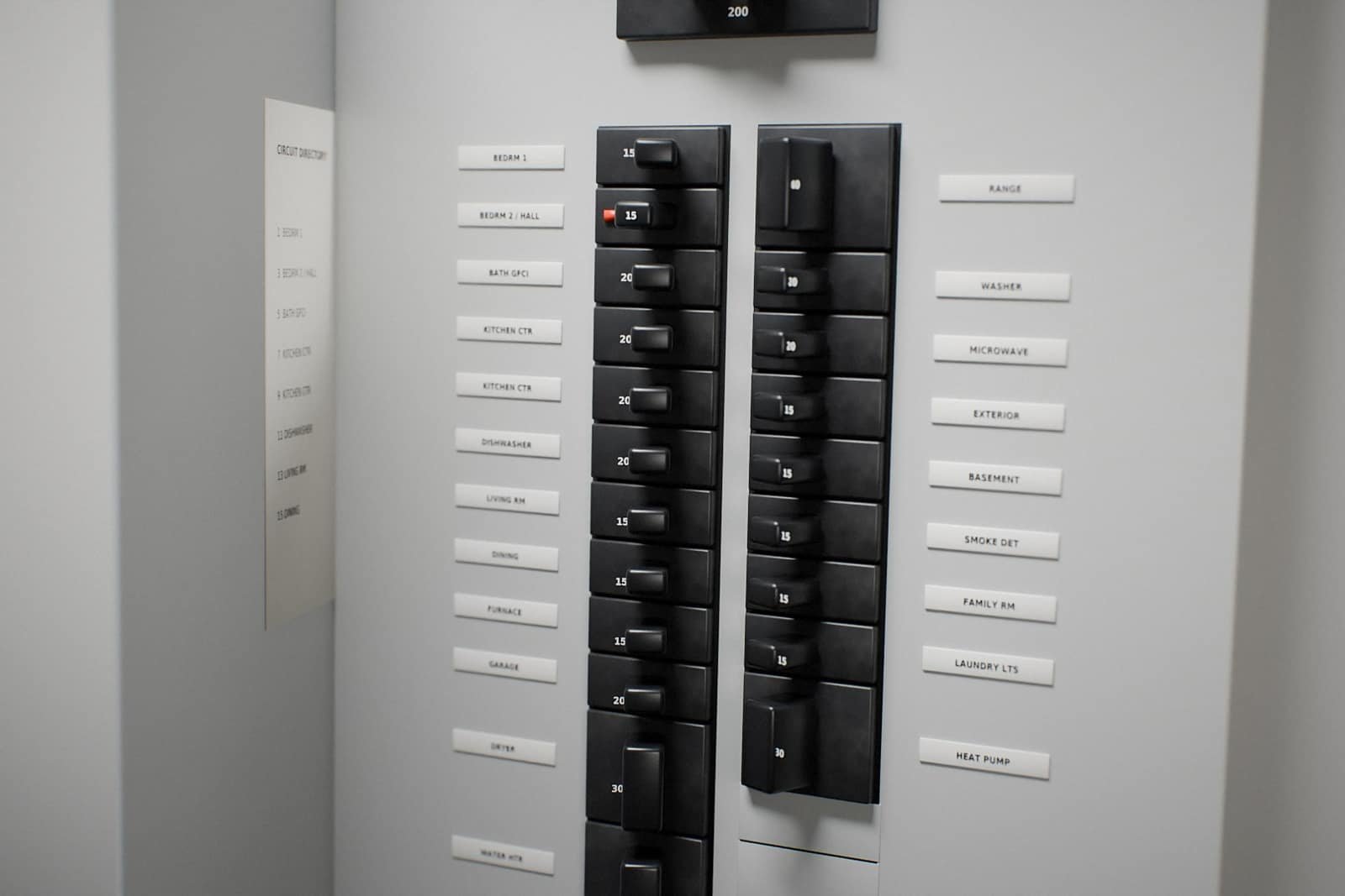 Open residential electrical panel with labeled breakers and one tripped breaker in the middle position