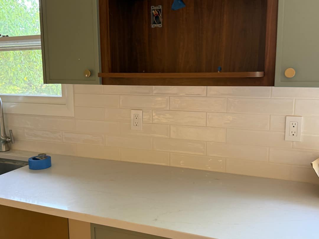 Electrical outlets installed on a tiled backsplash in a renovated kitchen.