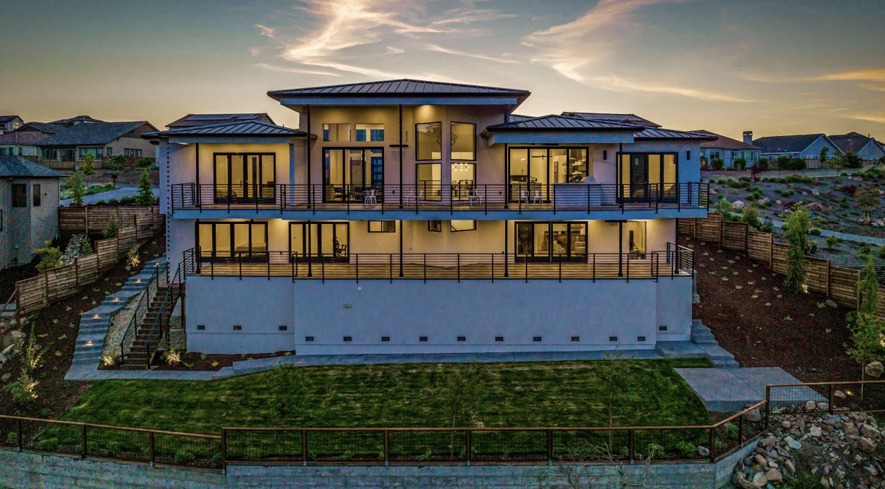 Rear view of a luxury custom home with illuminated outdoor living areas